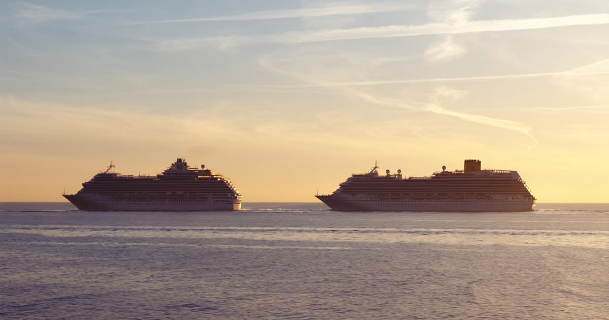 Two large cruise ships passing each other at sea in opposite directions at golden hour