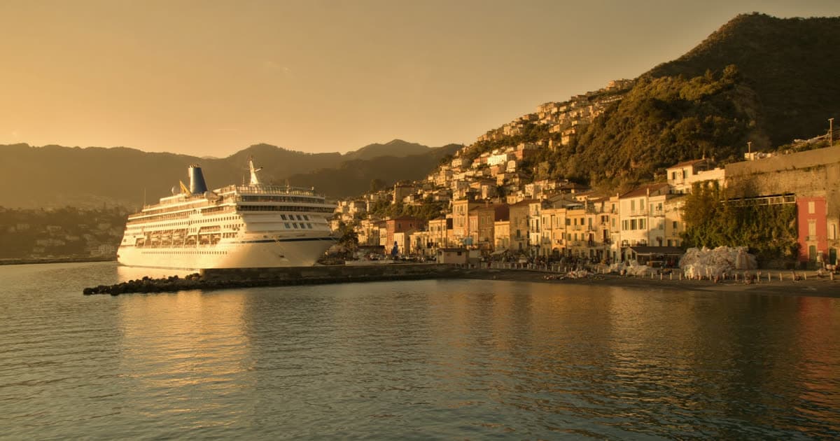 A Costa Cruises style ship in a Mediterranean harbour at golden hour