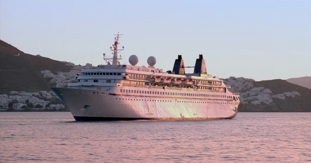 A mid-size Oceania style ship anchored off a Mediterranean coastline