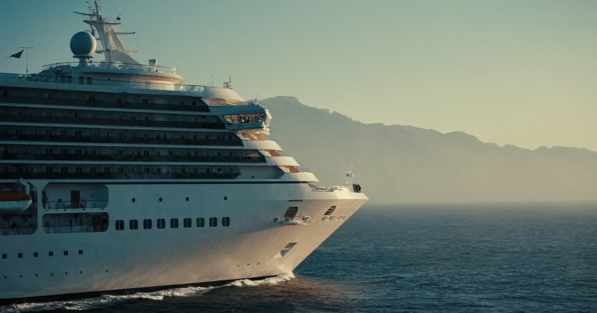 A modern Virgin Voyages style ship at sea with an open upper deck