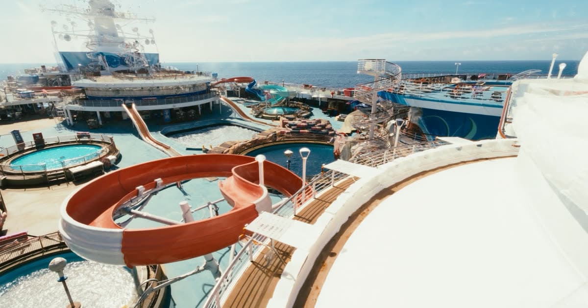 A large family cruise ship with water slides against a bright sky