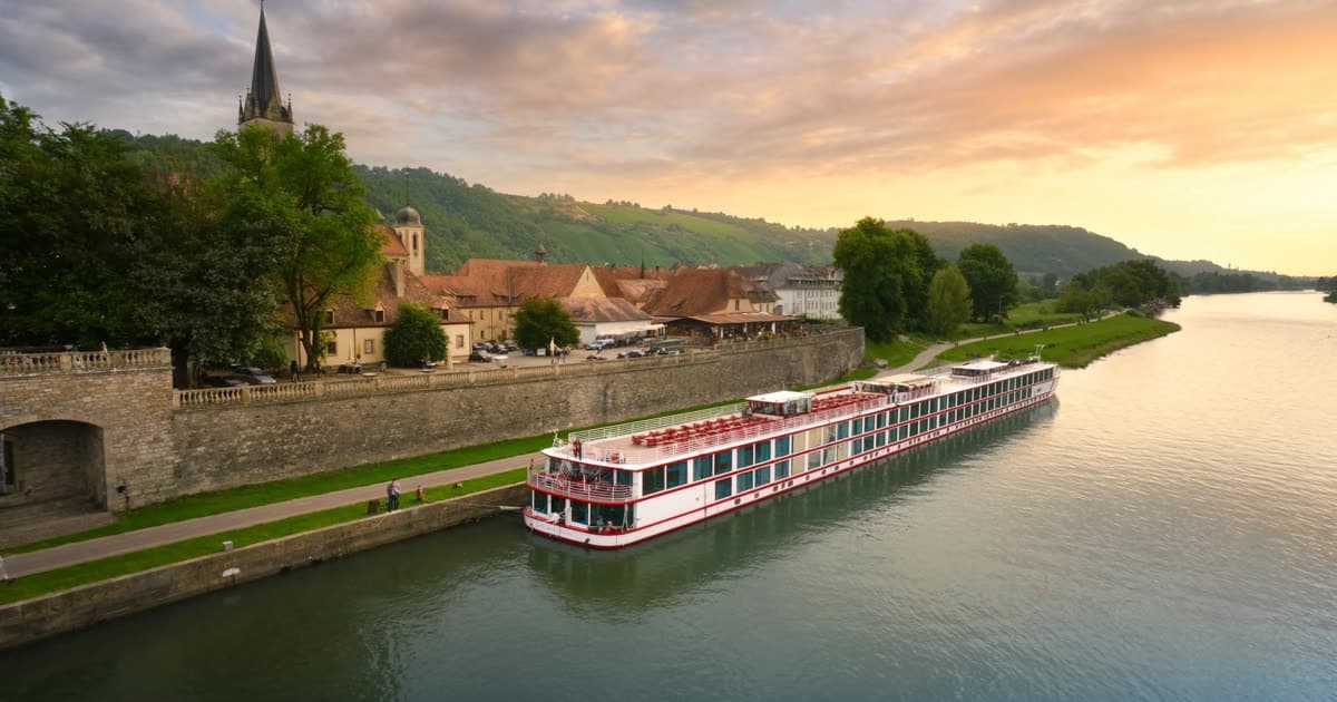 A long low river cruise vessel moored beside a European riverside town