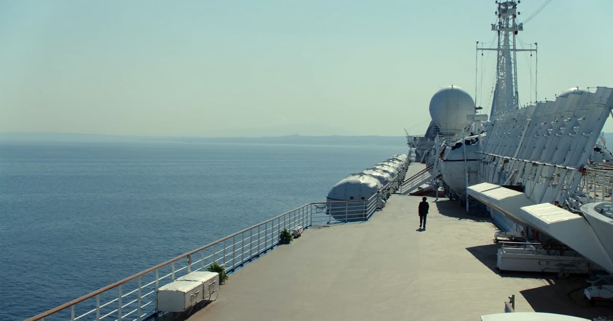 A mid-size cruise ship on a calm sea under soft light