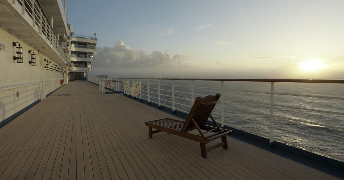 A cruise ship at sea with a single figure on an open deck