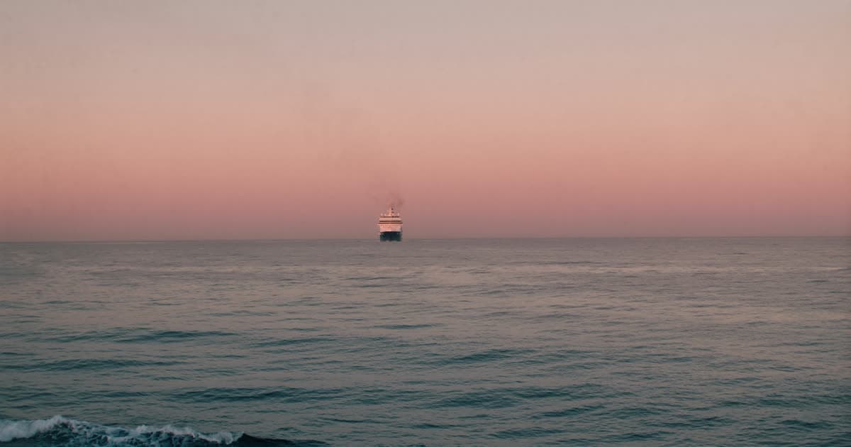 A cruise ship on open ocean at dawn on a long voyage