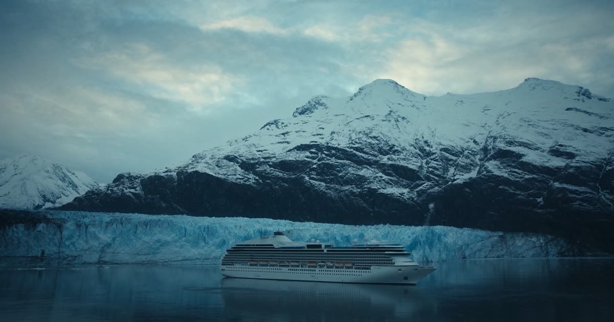 A cruise ship in an Alaskan fjord below snow-covered peaks