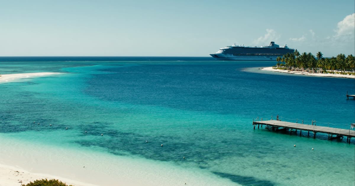 A cruise ship beside a Bahamian cay with pale sand and shallow turquoise water