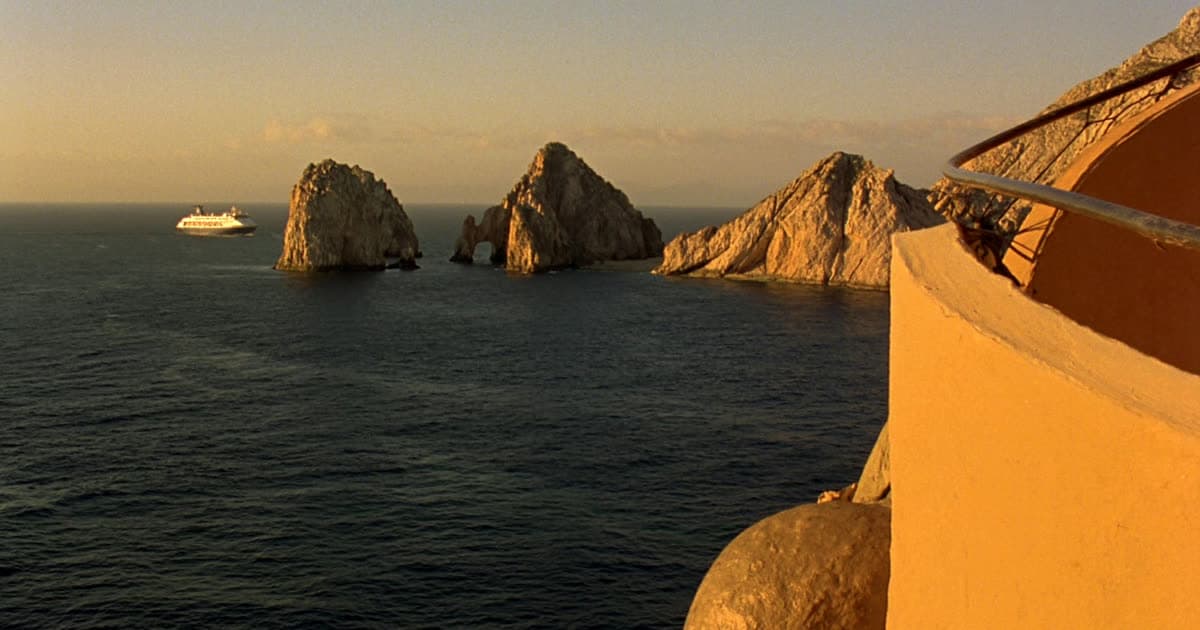 A cruise ship off a rocky Baja headland at golden hour