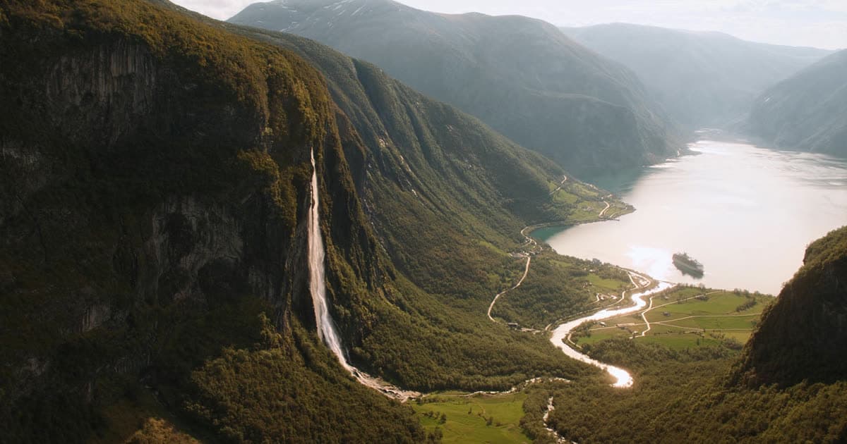 A cruise ship in a steep Norwegian fjord with waterfalls on the cliff face
