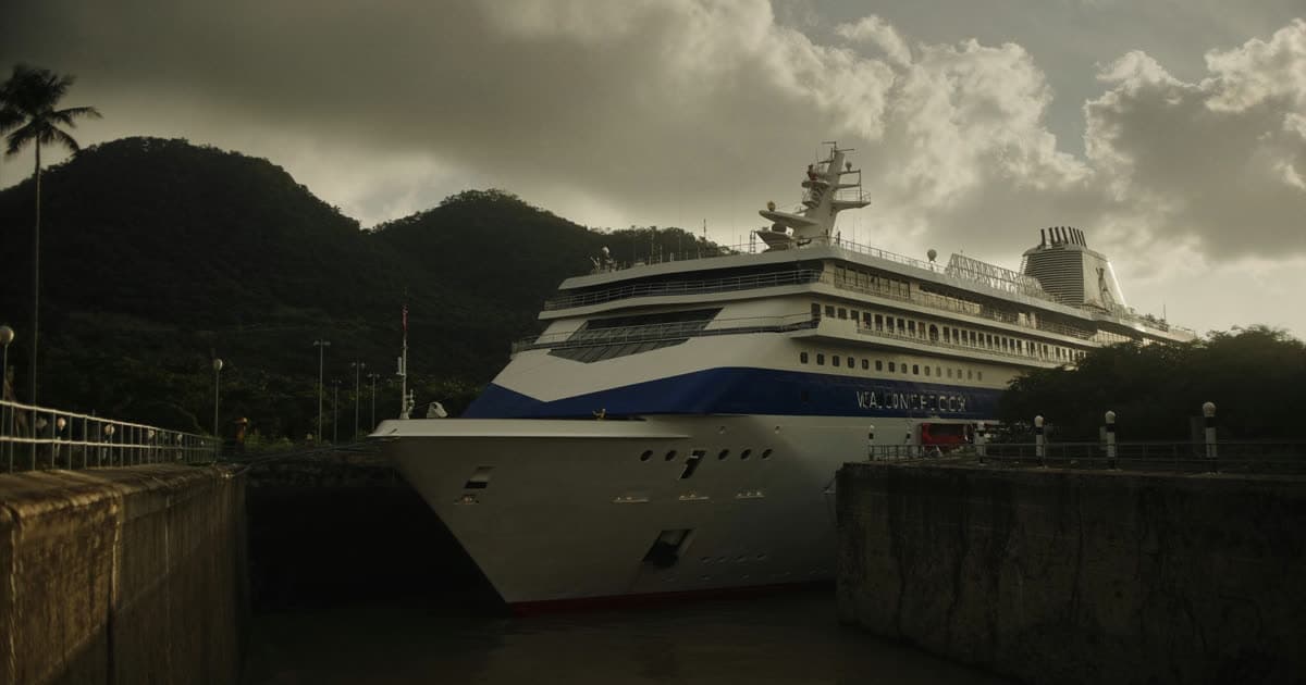 A cruise ship entering a narrow canal lock chamber flanked by concrete walls