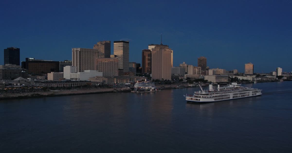 A cruise ship on the Mississippi River beside a low city skyline