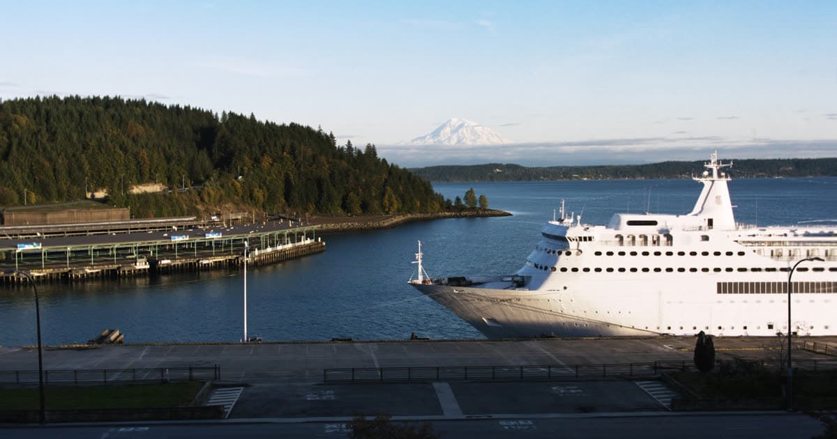 Cruise ships at a Pacific Northwest terminal with forested hills behind