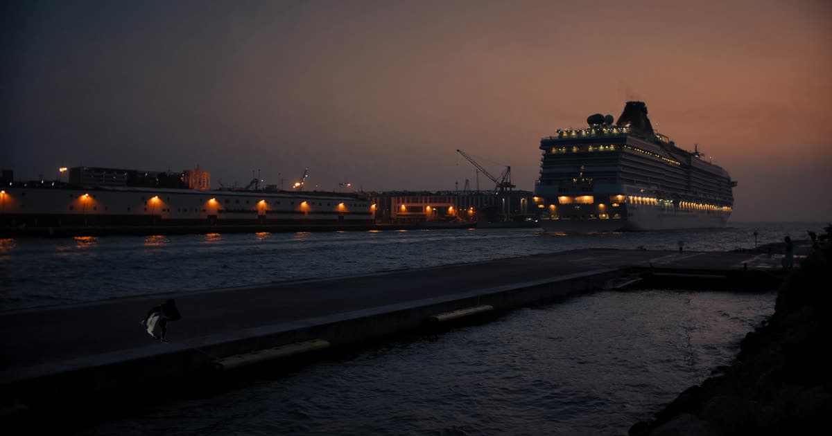 A cruise ship departing at dusk with empty berth space behind