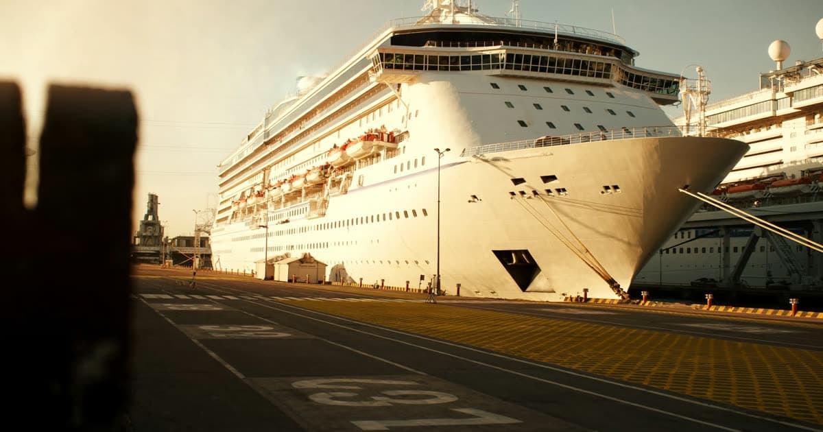 A cruise ship at a local port with cars arriving at the terminal