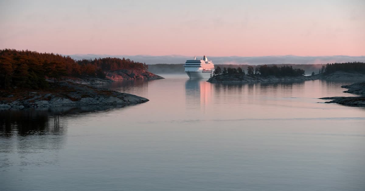 A cruise ship threading a Baltic archipelago at dawn