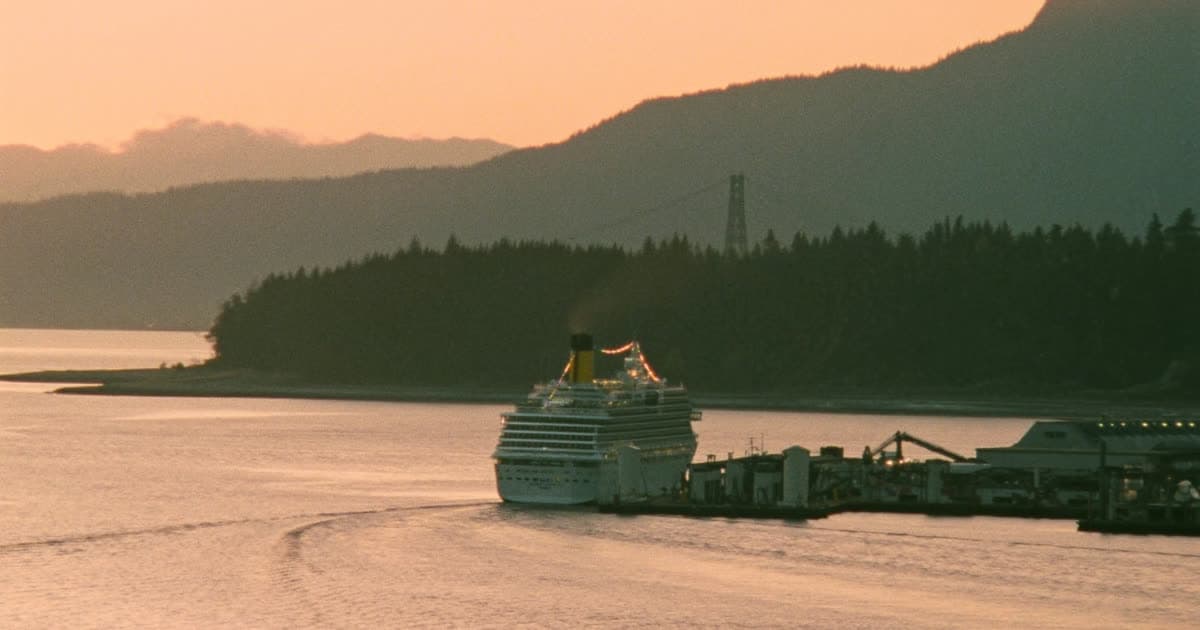 A cruise ship departing a Pacific Northwest harbour beneath coastal mountains